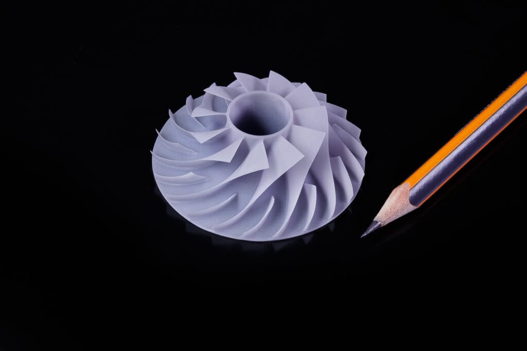 Pièce à ailettes imprimée en résine à côté d’un crayon pour montrer son échelle